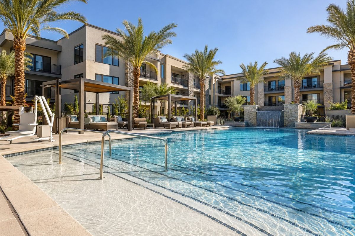 Aerial view of an apartment courtyard pool, spa, and cabanas with the Las Vegas valley beyond